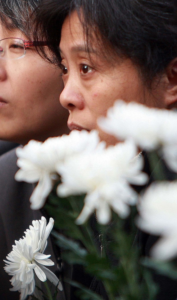 2010年11月21日是上海11·15大火灾后第七天,许多市民手持白花自发来