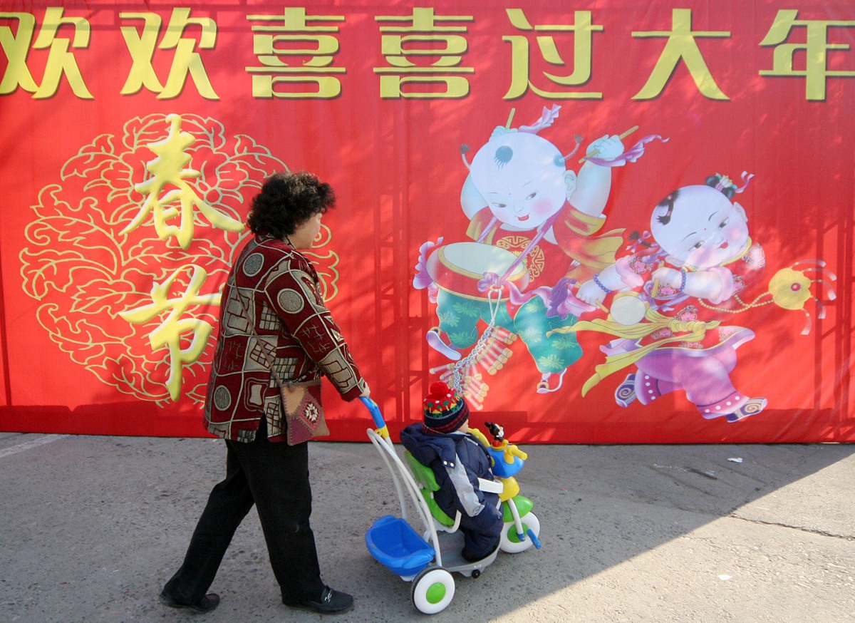 2007年2月1日,北京春节年货商品采购交易会开幕,市民推着孩子从欢欢喜