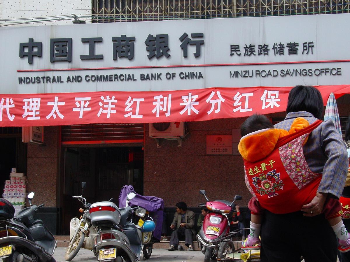 背着小孩的妇女从工商银行"代理太平洋红利来分红保险"前经过+++_+++
