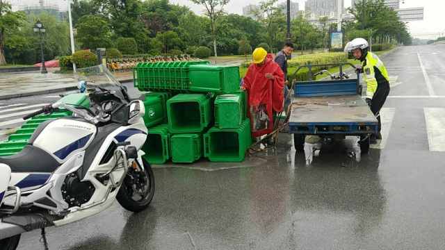 三轮车疑超载侧翻,巡警冒雨捡货物