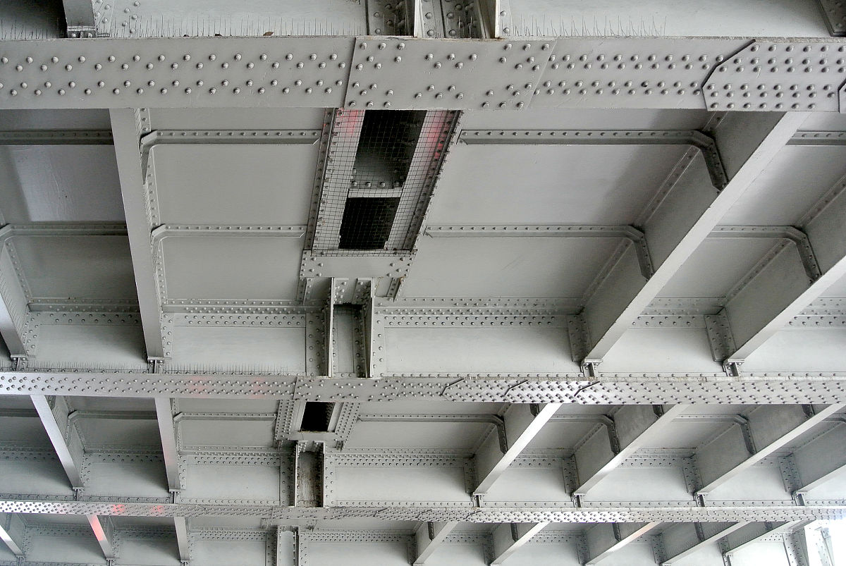 优化并翻译一下这句话使之具有学术规范性；同时试件由钢连梁首先屈服逐渐转变为钢连梁与组合墙肢同步屈服。