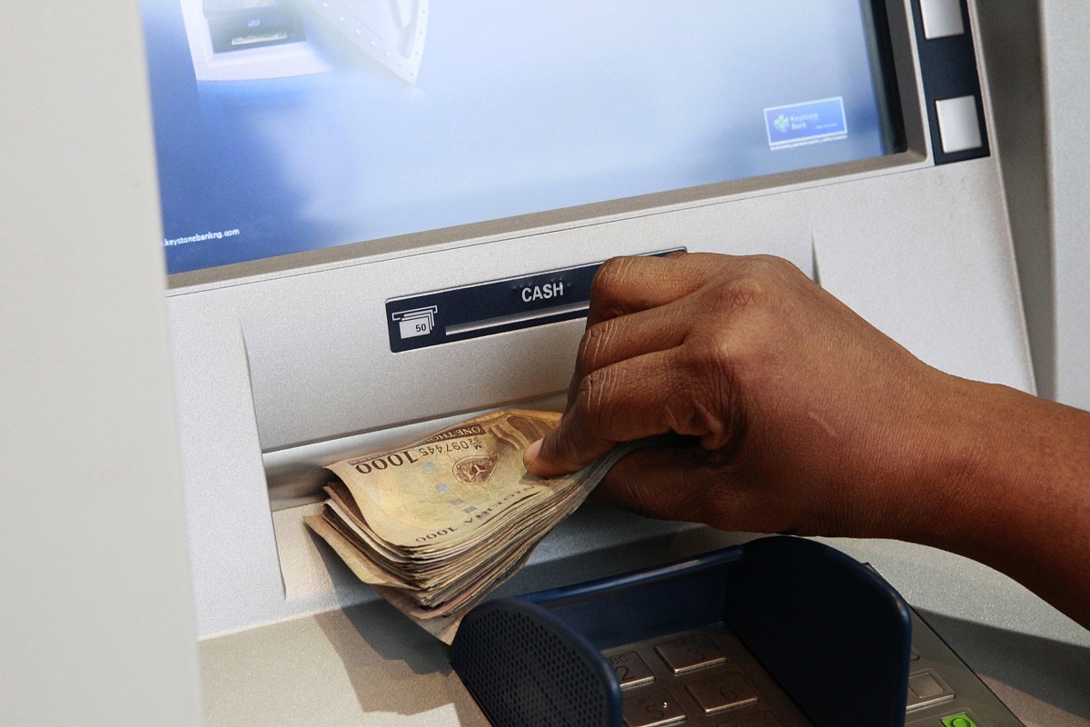 a woman takes nigerian naira from a bank's automated teller mach