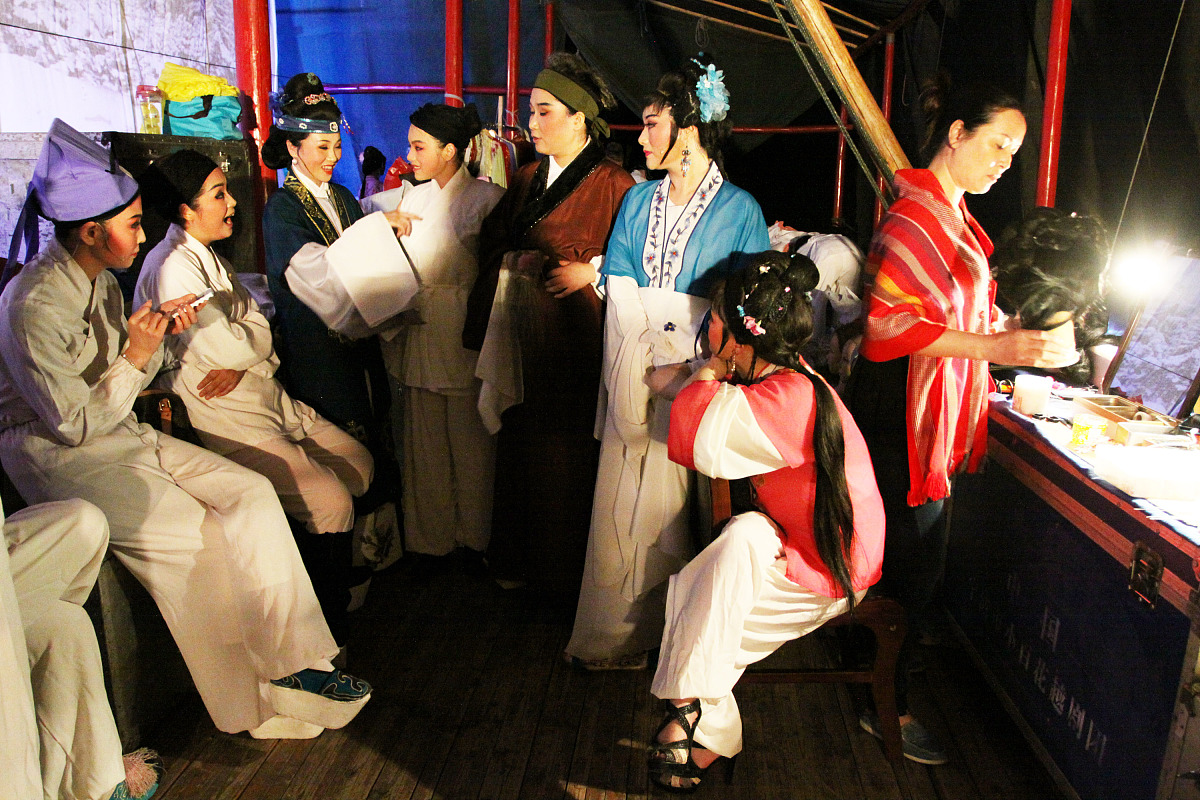 请描写一下一个老婆婆带着1一个年轻人和一个小孩儿在神社参拜一个女巫的画面