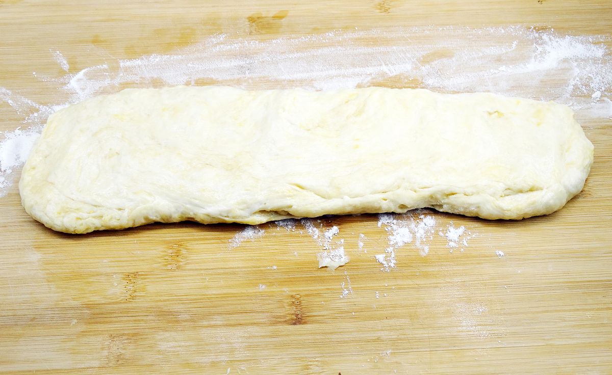 图为香酥小油条的制作过程 打开保鲜膜,将面团抻成长条状.