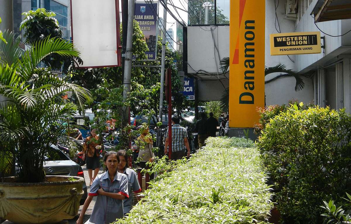 indonesians walk past a bank danamon sign board outside the bank