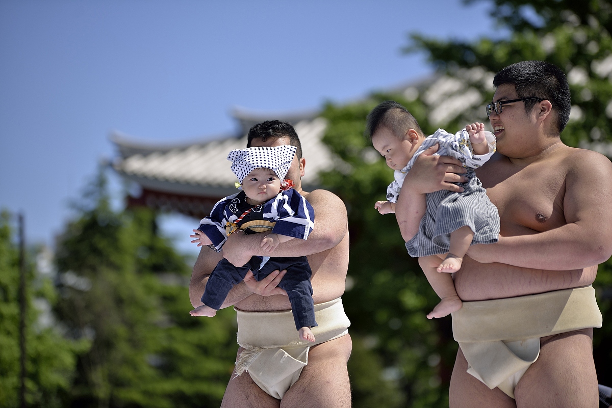 当地时间2016年4月29日,日本东京,相扑选手抱着小孩参加"宝宝哭"相扑