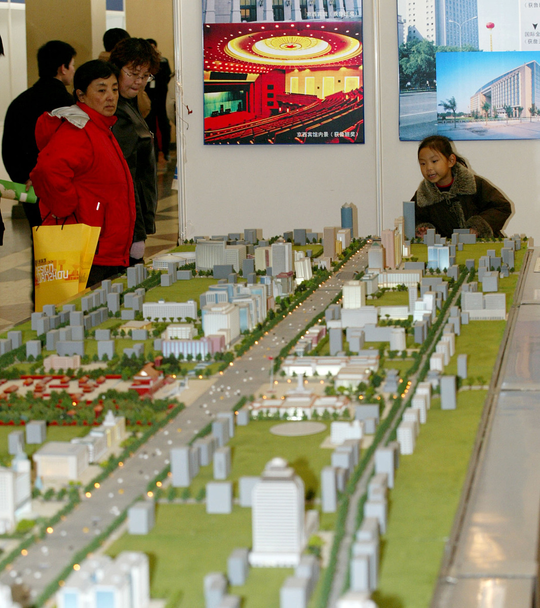 沙盘中摆放了较多的建筑物、车辆、人各个地方的人围绕着篮球馆观看篮球比赛车辆排成长龙在沙盘的最外圈川流不息