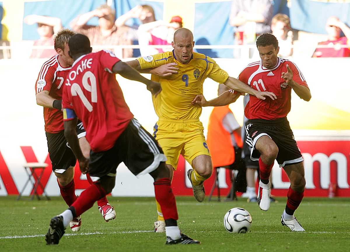 sweden's fredrik ljungberg (c) is put under pressure from trinid