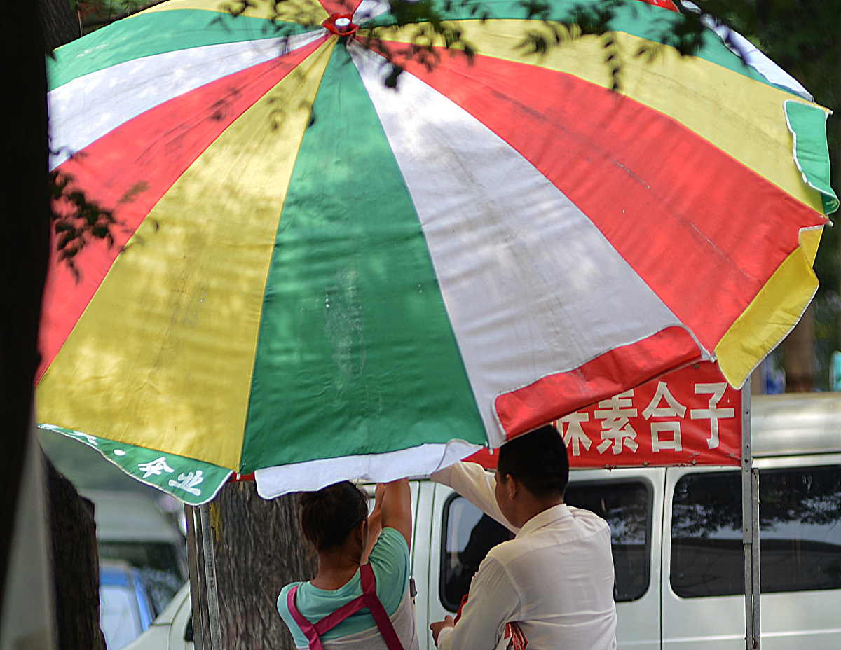 2013年8月7日,商家在山东邹平县街头撑遮阳伞,该地当日最高气温达到36