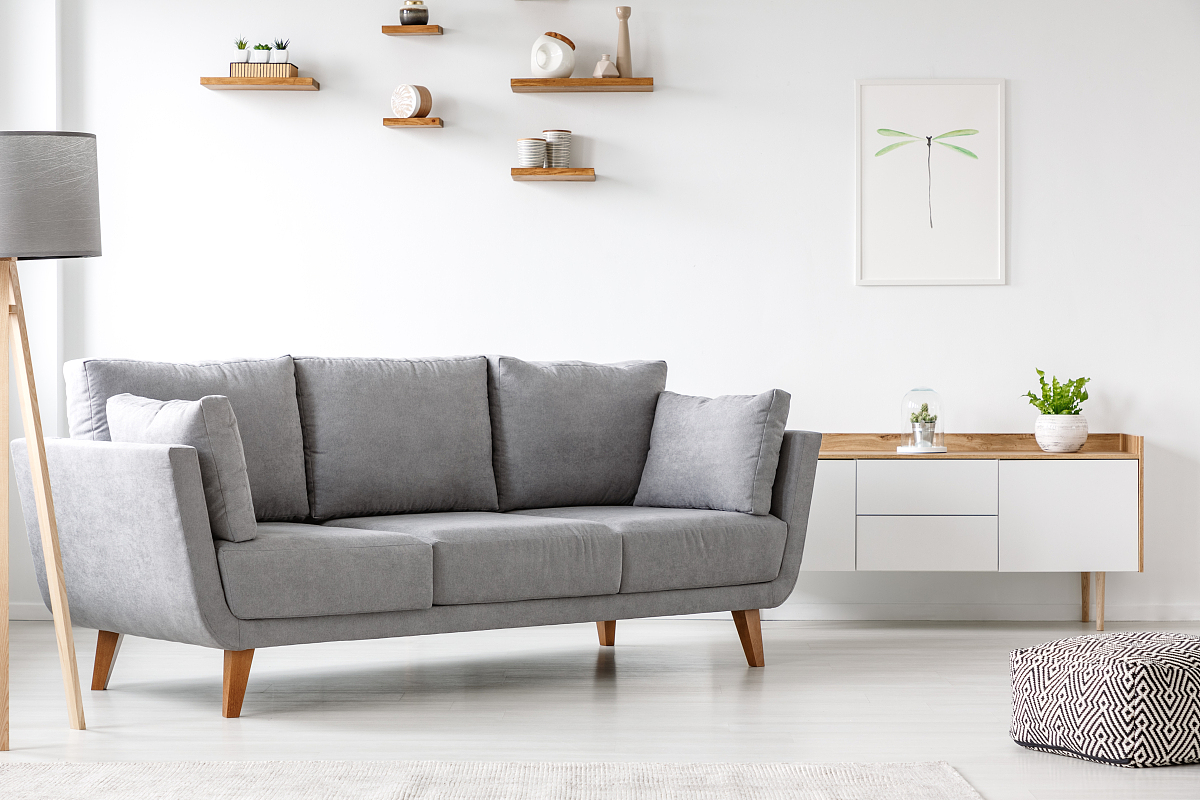 simple, gray sofa standing next to a white cupboard in living ro