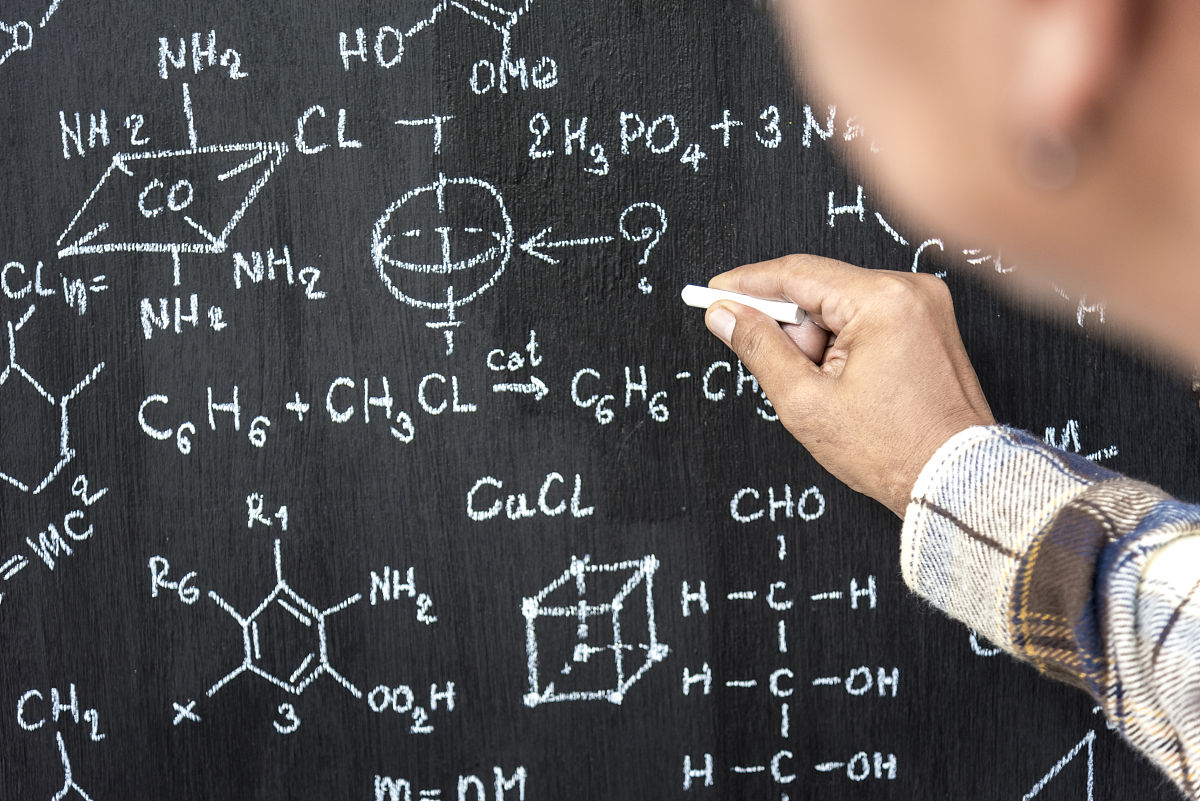 tutor writing physical chemical formula on blackboard, education