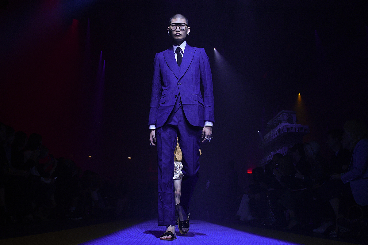 周总：大家好啊今天是我们公司的时尚日希望大家都穿的很时髦。写出来周总的动作。越详细越好。50字左右周总的化妆和现场的灯光设计