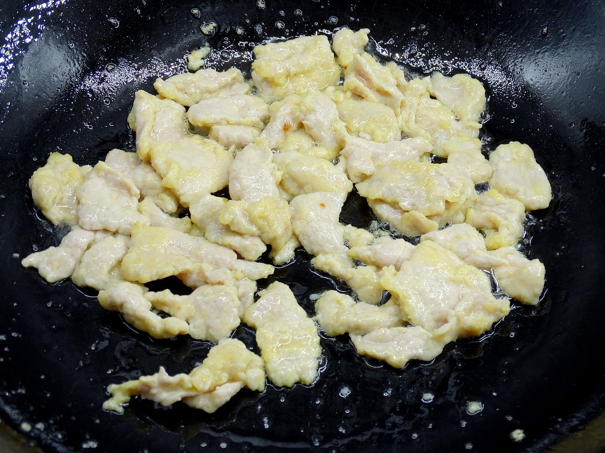 图为木须肉的制作过程 中火凉油下入肉片滑散.