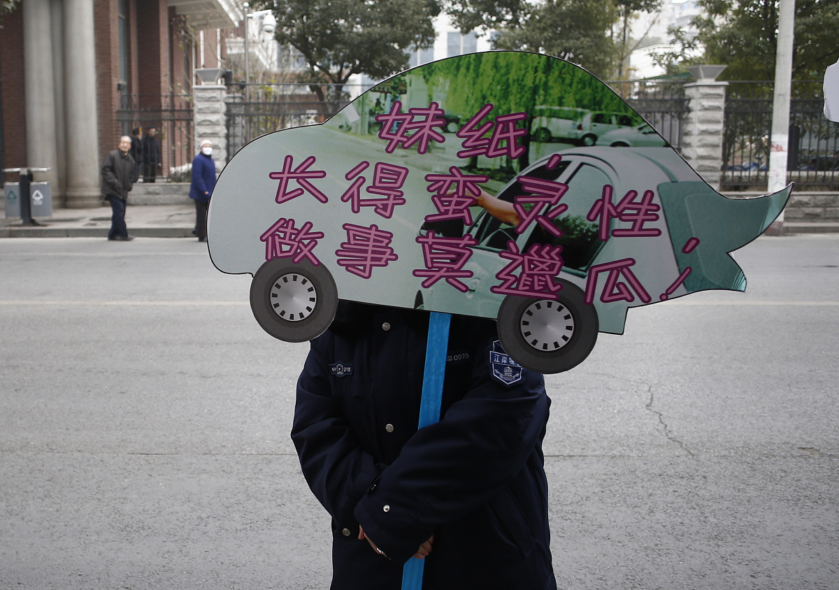 2013年1月17日,武汉城管执法队员在大街上举着牌子宣传禁止车窗抛物,