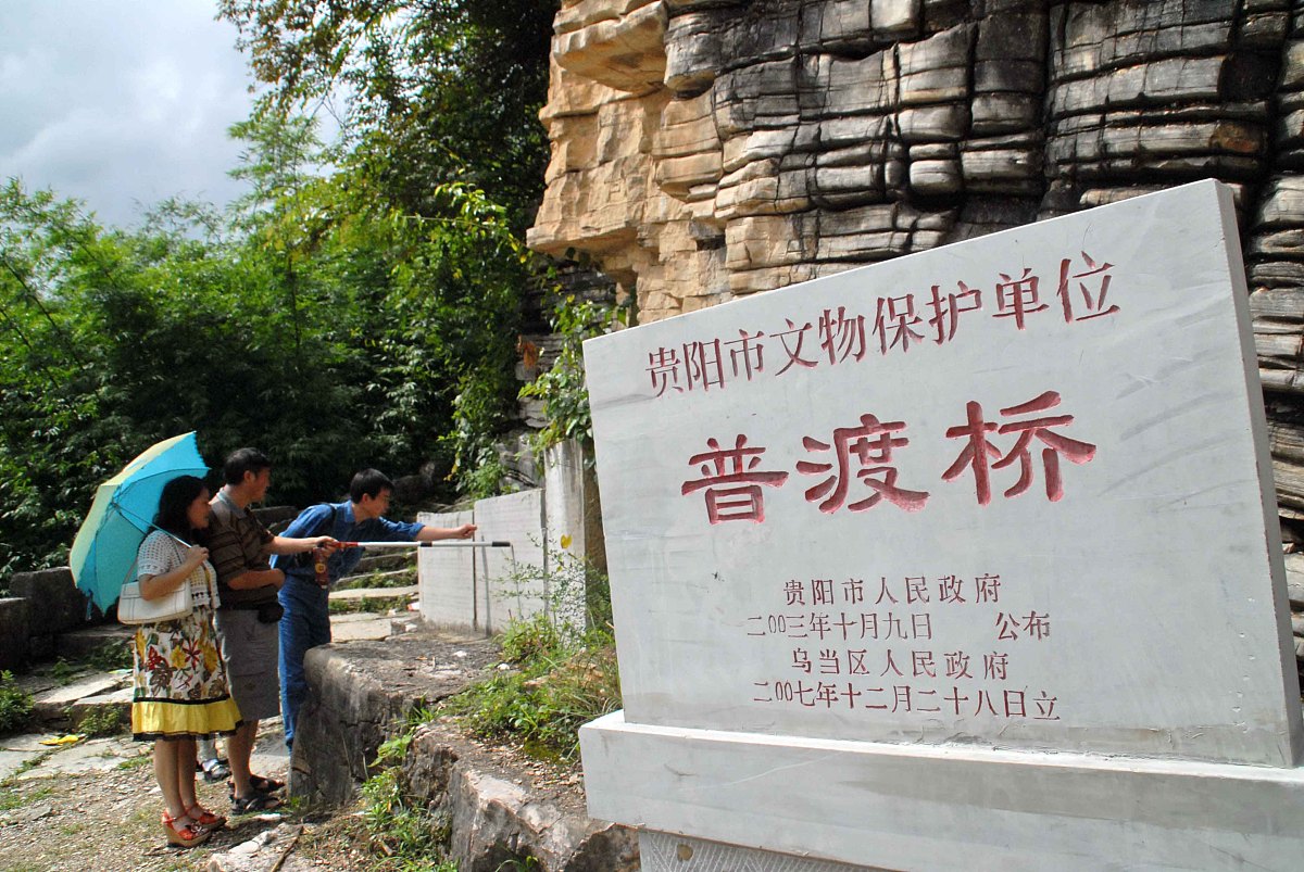 2008年7月3日,贵州贵阳,游客在观看建桥时的古碑文.+++_+++古桥石雕