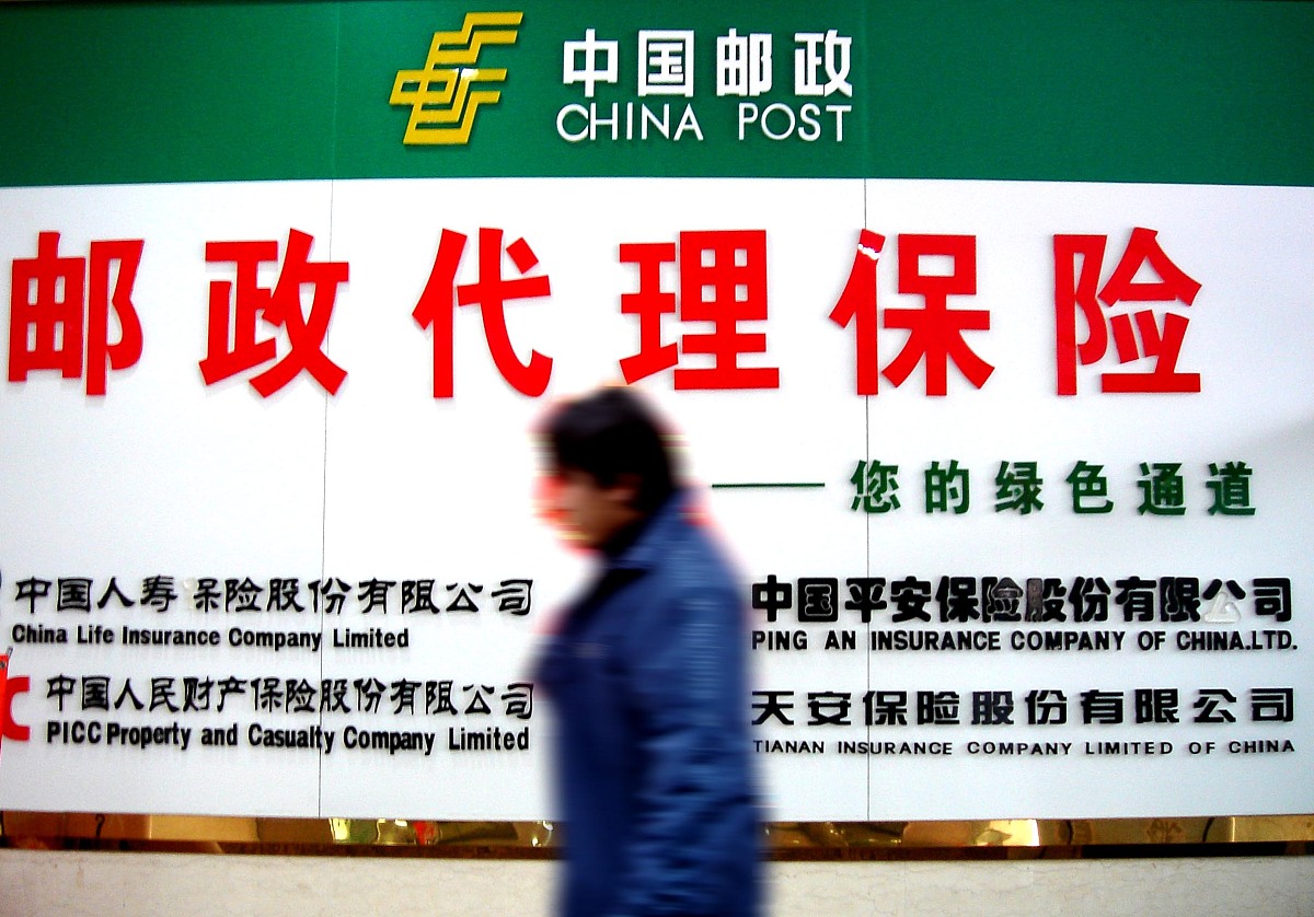 2005年11月24日,安徽淮北市一市民从邮政代理保险的宣传牌前经过.+++_