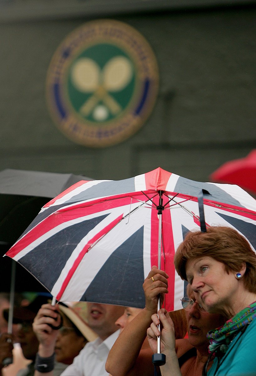 london - july 05:  fans wait under umbrellas as the game between