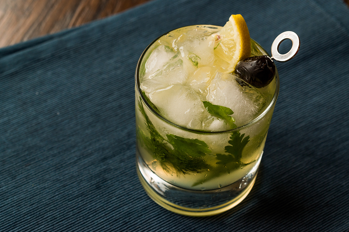 dillionaire cocktail with dill, gin, parsley, lemon, olive and c