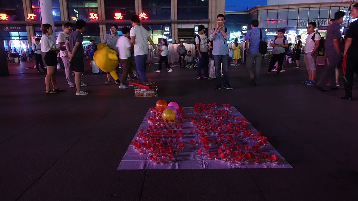 把下面内容进行改写洗稿3月29日根据陕广电报后浪视频报道近日在四川达州一段男子带鲜花下跪的视频引发关注。视频中一名身穿白色衬衫的男子手捧99朵玫瑰在一家餐厅门口向一名身穿红色连衣裙的女子下跪求婚。周围的人群纷纷围观为他们加油打气。