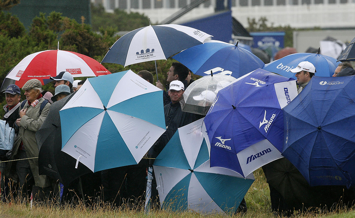 spectators cover from the rain during round one of the open cham