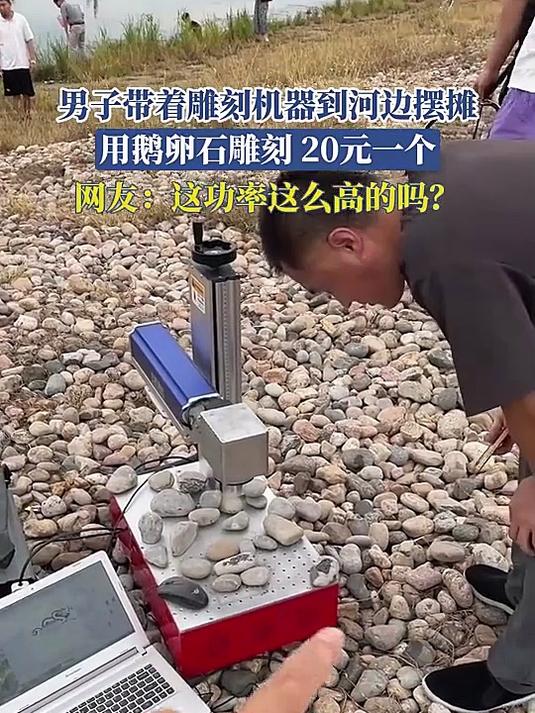 男子带着雕刻机器到河边摆摊,用鹅卵石雕刻,20元一个