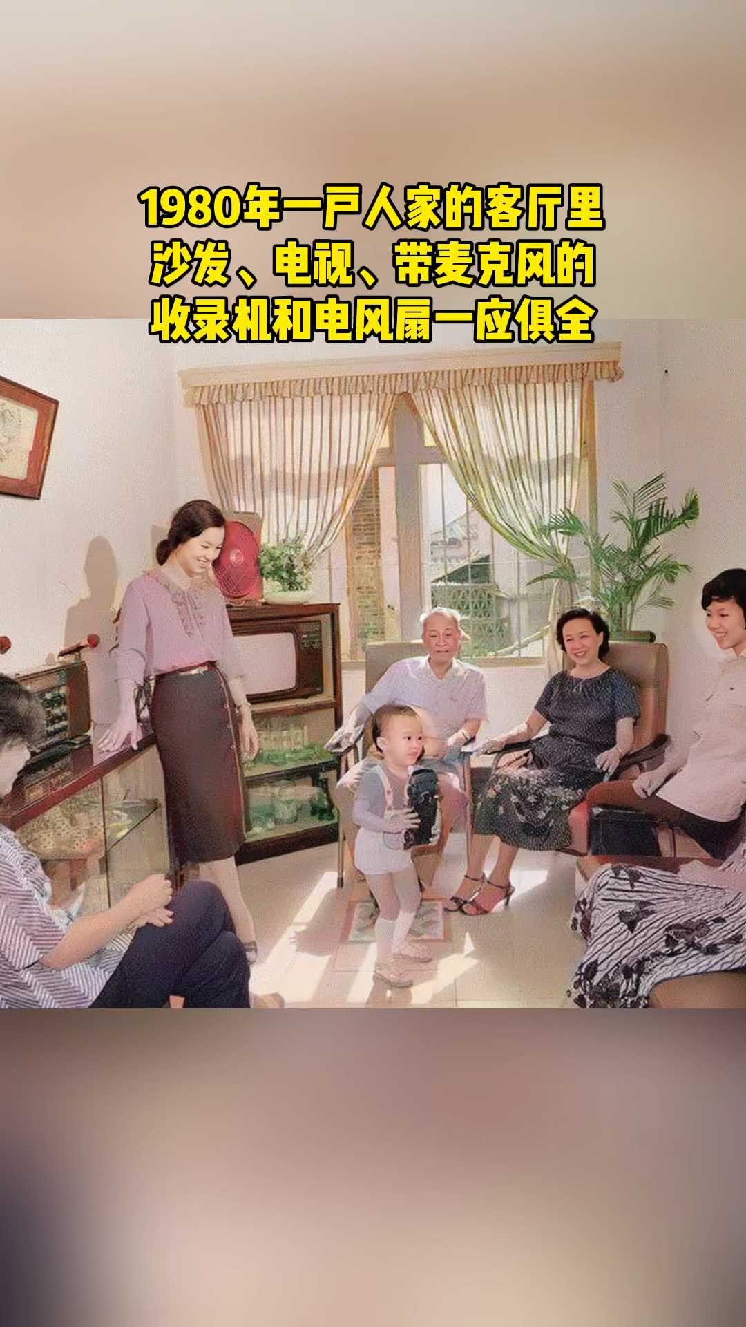 这张照片拍摄于1980年,一户人家的客厅里,沙发、电视、带麦克风的收录机和电风扇!