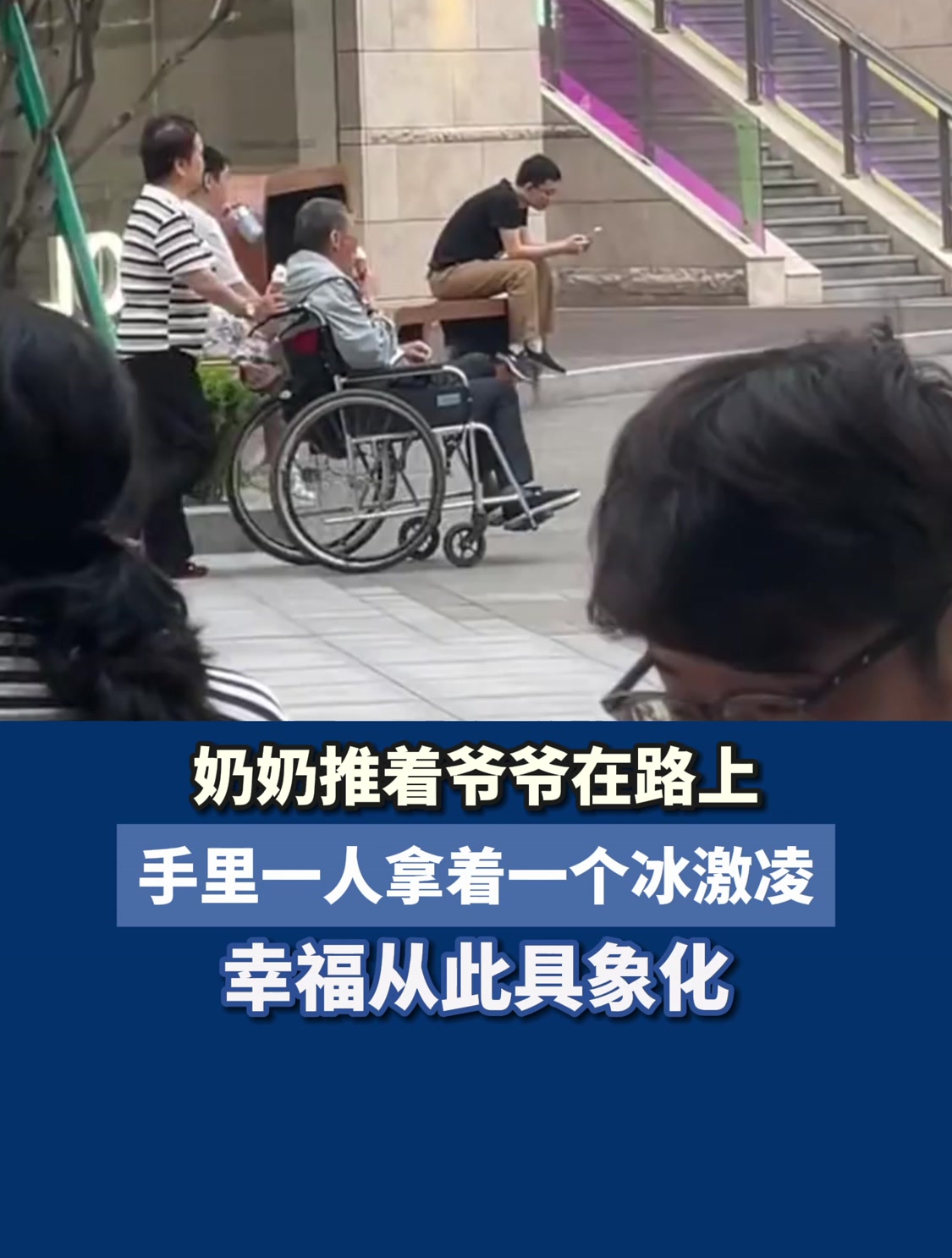 奶奶推着爷爷在路上,手里一人拿着一个冰激凌