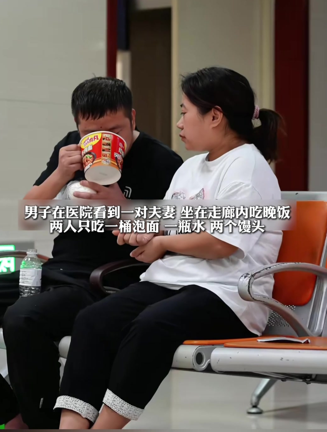 在医院走廊内一对夫妻在吃晚饭,两人吃一桶泡面一瓶水和两个馒头