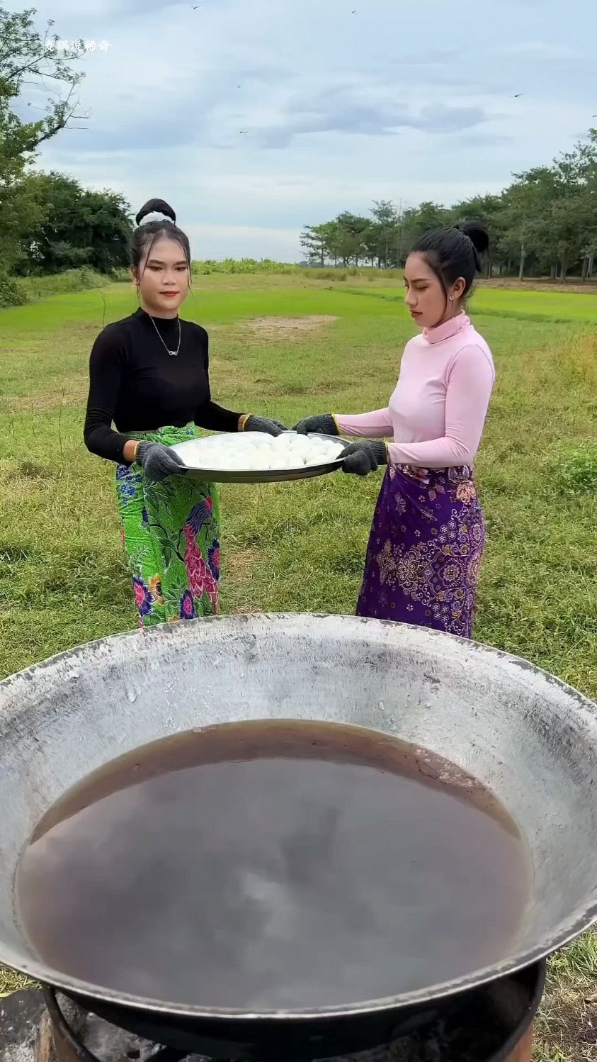 两个女人将一大盘鸭蛋,全都倒进油锅里,剥开壳,做出美味的鸭蛋