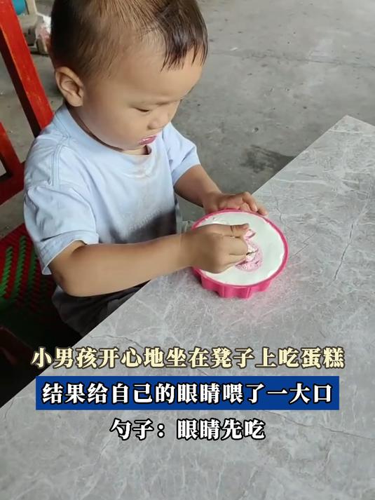 小男孩开心地坐在凳子上吃蛋糕,结果给自己的眼睛喂了一大口
