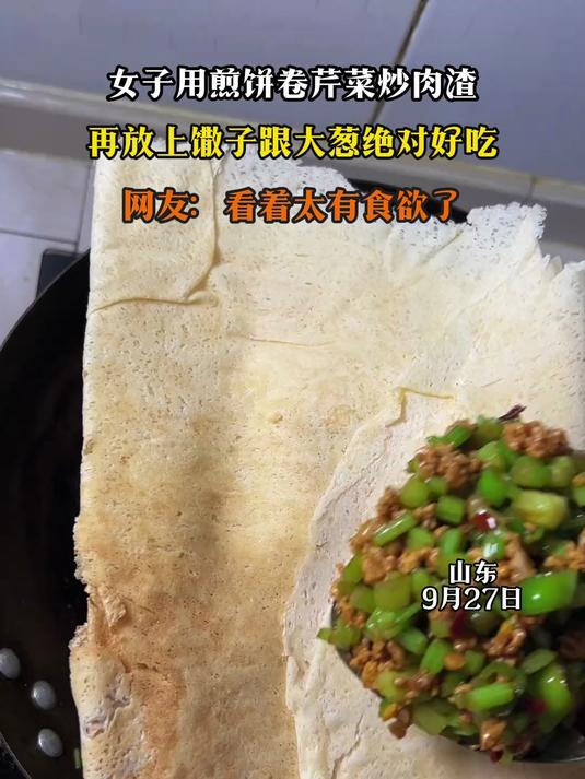 女子用煎饼卷芹菜炒肉渣,再放上馓子跟大葱绝对好吃
