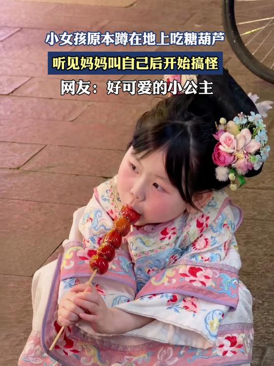 小女孩原本蹲在地上吃糖葫芦,听见妈妈叫自己后开始搞怪