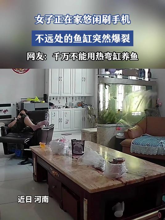 一女子在家里客厅刷手机,突然鱼缸爆了,水像瀑布一样涌出