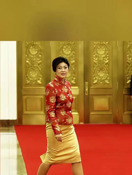 英拉身着红金唐装，杏色半裙搭配得体，红毯上步履从容