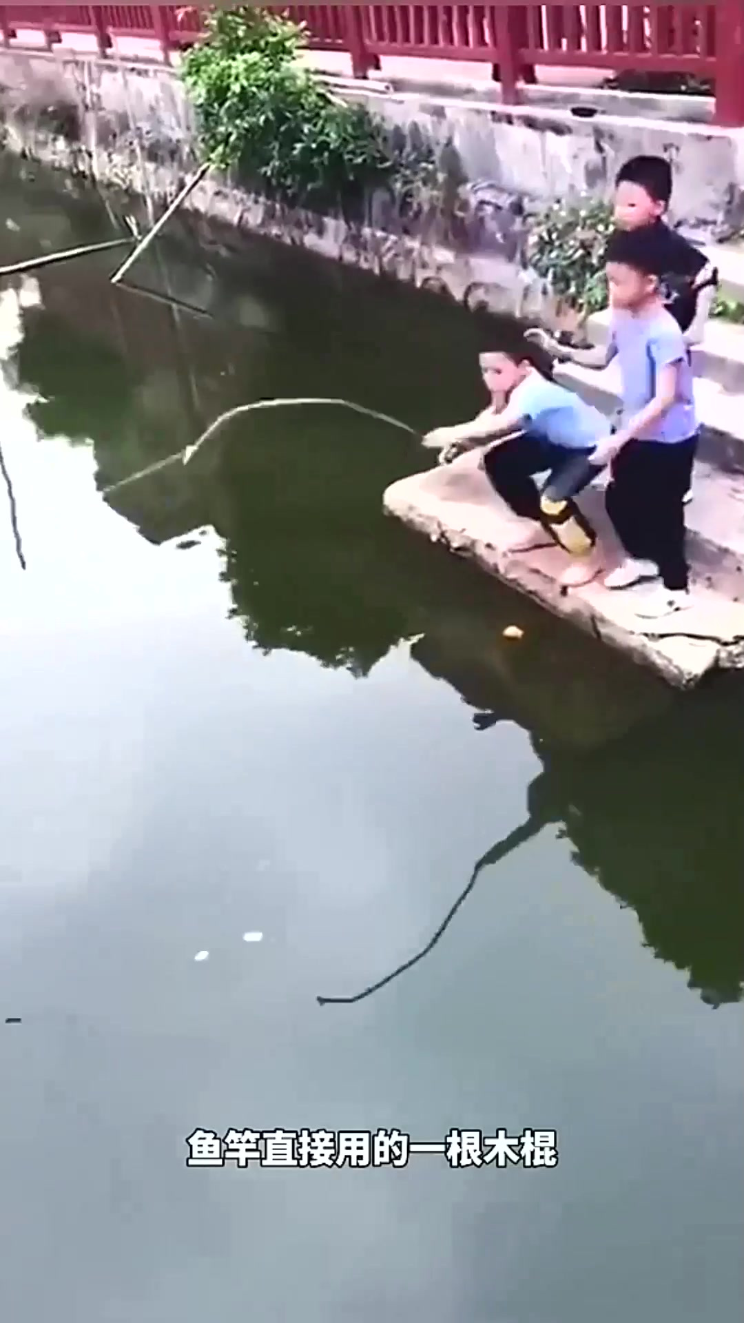三个小男孩在河边用木棍钓鱼