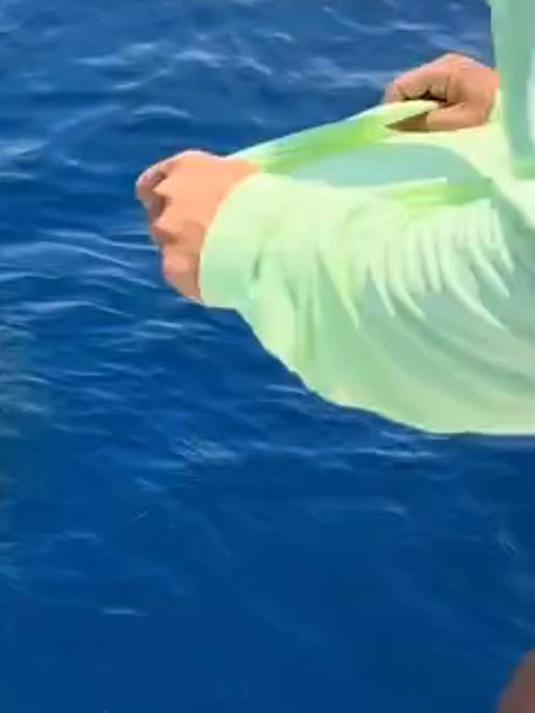 国外一男子用衣服捕鱼，把衣服卷起一头跳进鱼群里