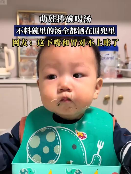 萌娃捧碗喝汤，不料碗里的汤全都洒在围兜里