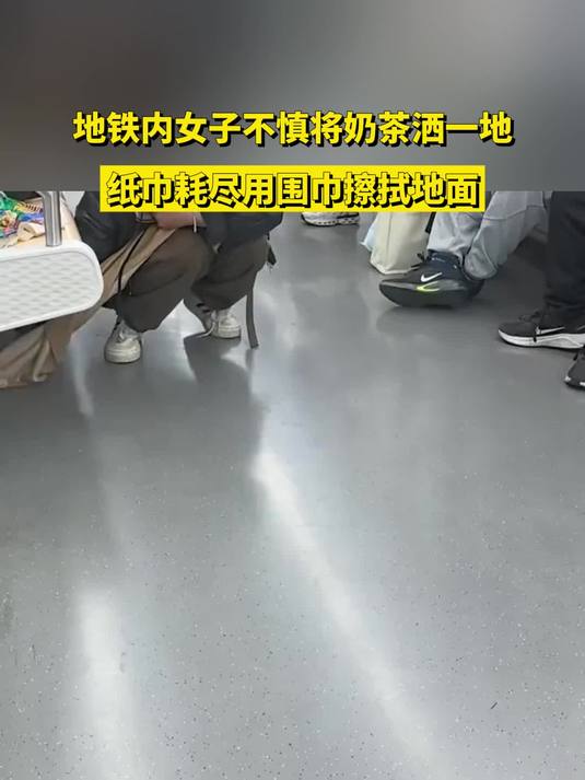 地铁内女子不慎将奶茶洒一地，纸巾耗尽用围巾擦拭地面
