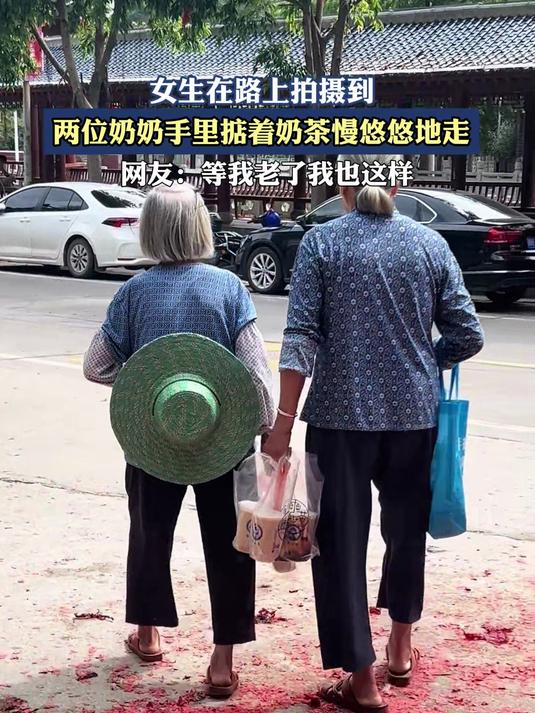 女生在路上拍摄到,两位奶奶手里掂着奶茶慢悠悠地走