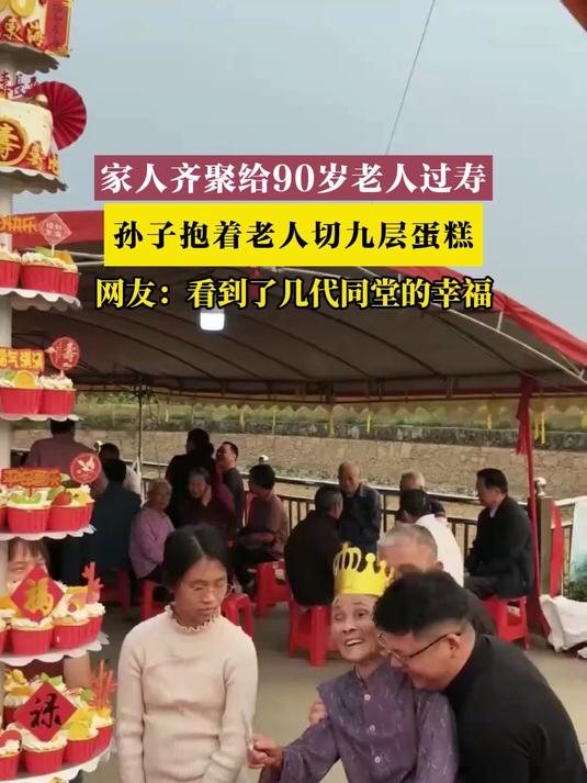 家人齐聚给90岁老人过寿，孙子抱着老人切九层蛋糕