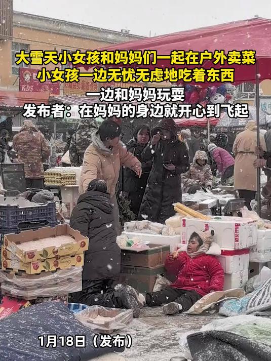 大雪天小女孩和妈妈们一起在户外卖菜，小女孩一边吃东西，一边和妈妈玩耍