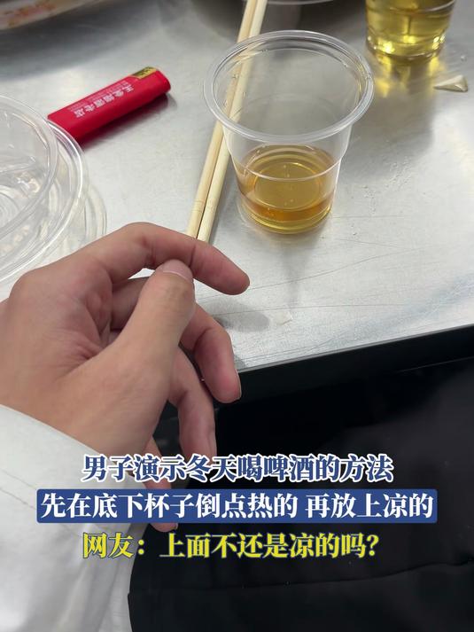 男子演示冬天喝啤酒的方法，先在底下杯子倒点热的，再放上凉的
