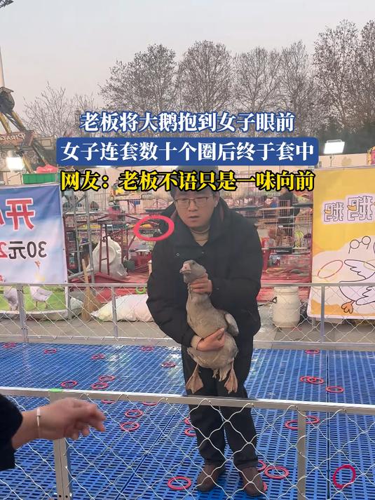 老板将大鹅抱到女子眼前，女子连套数十个圈后终于套中，网友：老板不语只是一味向前#我的新年一