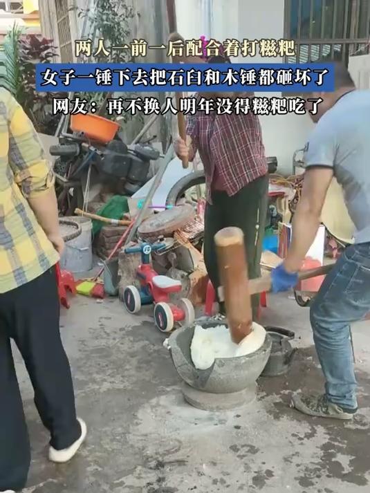 两人一前一后配合着打糍粑，女子一锤下去把石臼和木锤都砸坏了