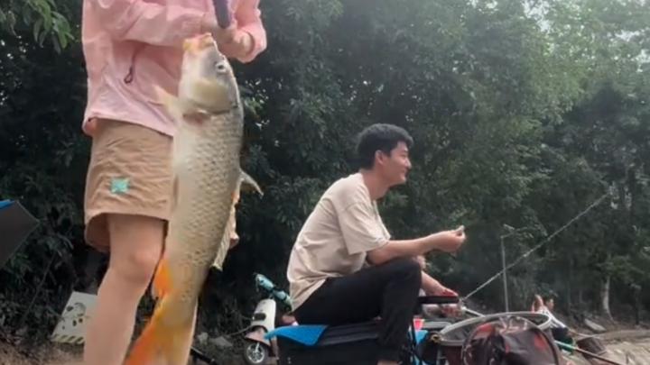 女生用木棍自制钓鱼竿,捡来旁人不要的鱼饵,不料一杆就中