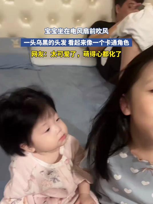 宝宝坐在电风扇前吹风,一头乌黑的头发,看起来像一个卡通角色