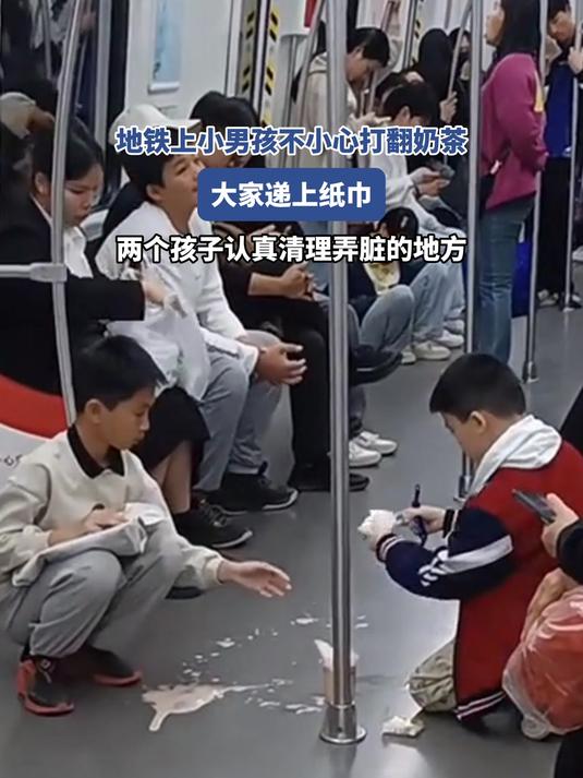 地铁上男孩不小心打翻奶茶,大家递上纸巾,两个孩子蹲下认真清理