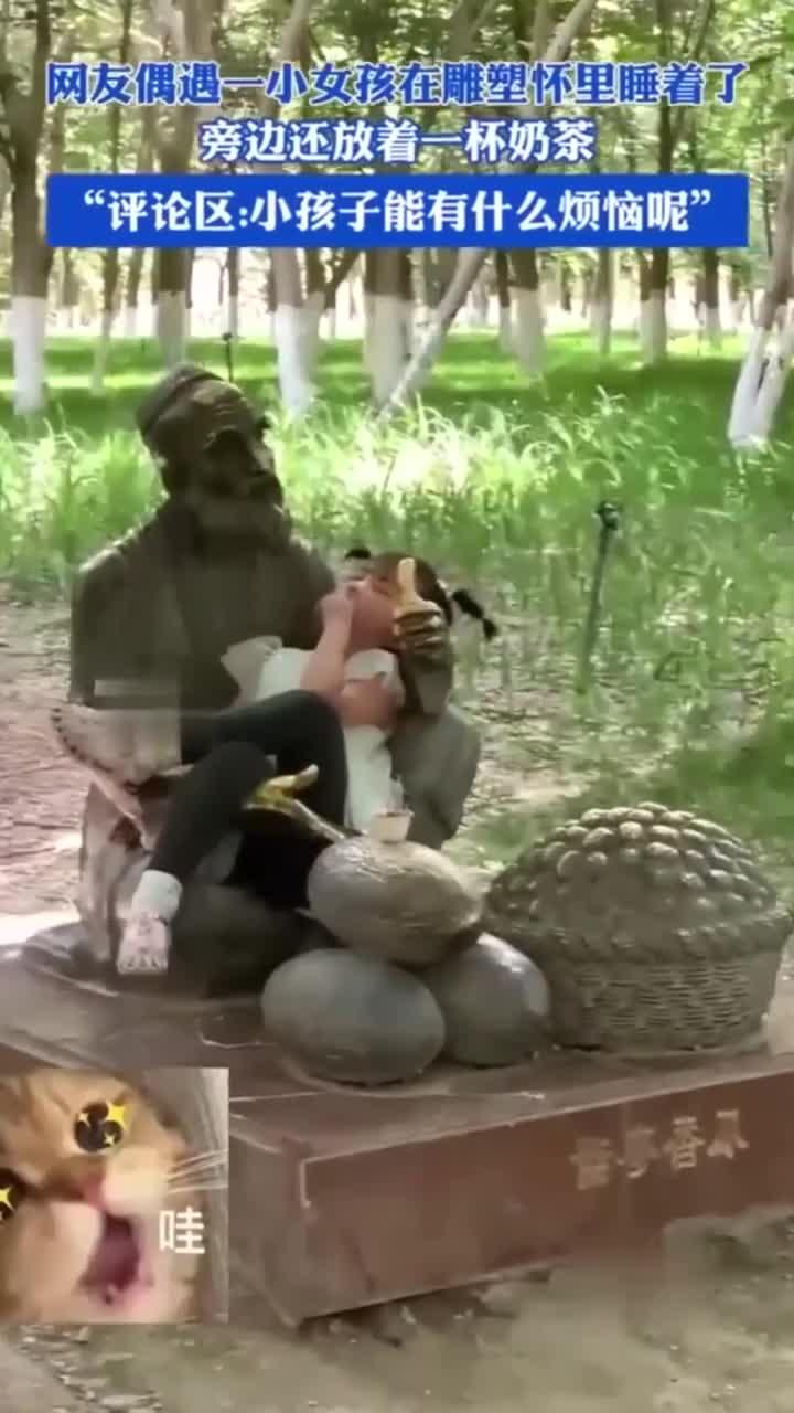 小女孩在雕塑怀里安然入睡，旁边奶茶恰到好处