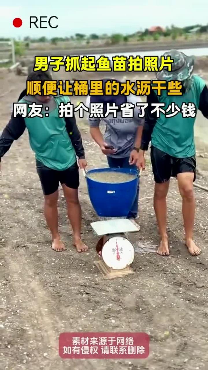 男子抓起鱼苗拍照片,顺便让桶里的水沥干些