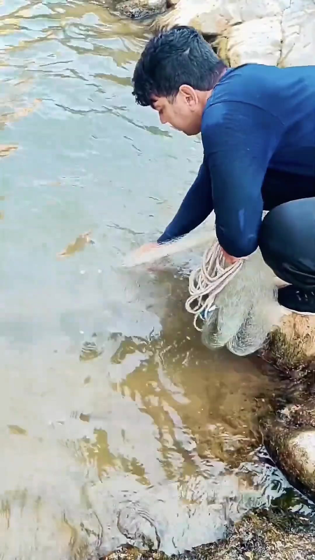 渔民在悬崖峭壁的深潭中撒网捕鱼,捕获两条草鱼!